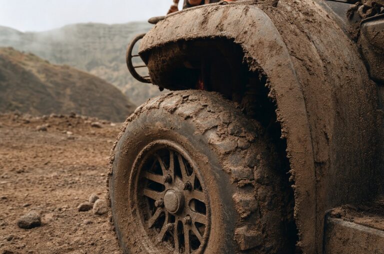 Close-up of a mud-caked ATV wheel and fender, stationary, sharp focus