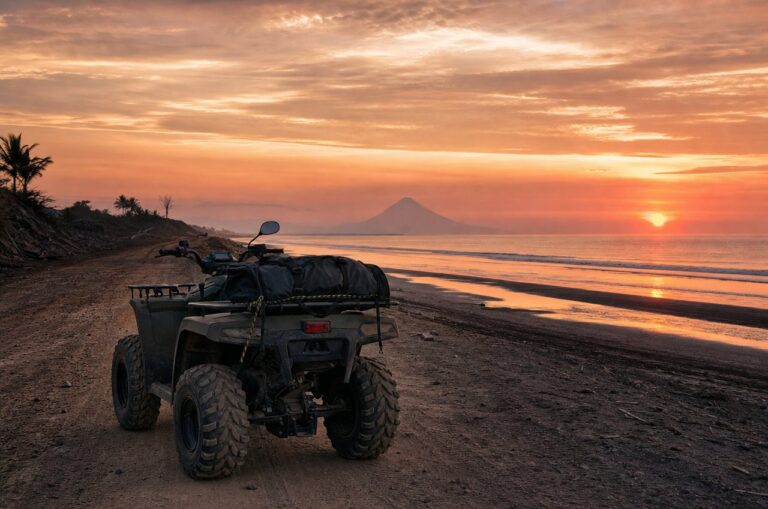 An ATV parked on a coastal dirt road at sunset