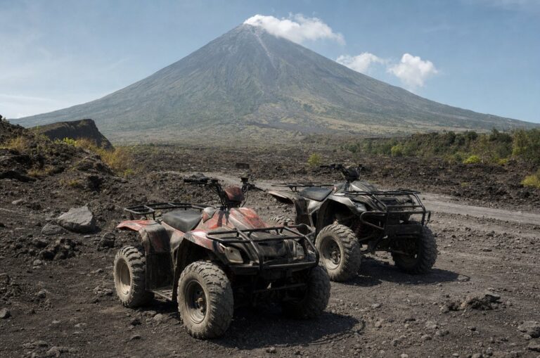 Two ATVs parked on the black lava trail with Mayon Volcano rising behind them